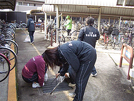 駐輪場のごみを丁寧に取り除く